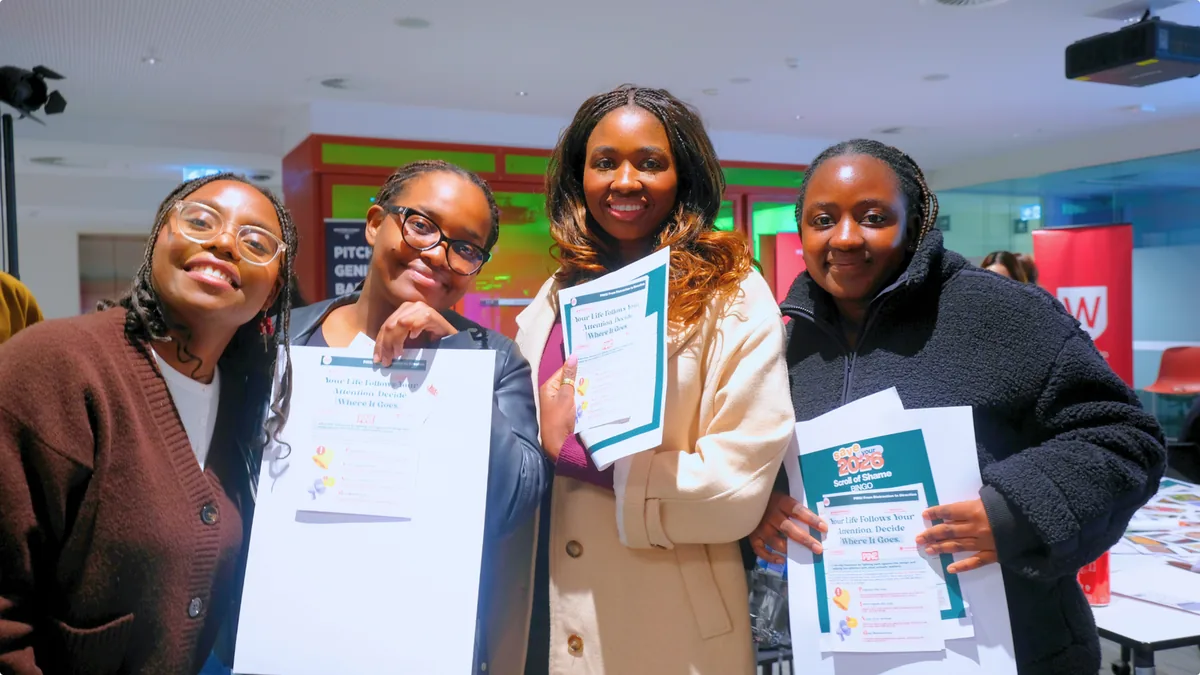 Four smiling participants holding their workshop worksheets